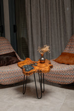 AI-styled view of Zitun Atelier table 091, an olive wood resin side table with black marble resin, in a lounge setting with a vase on the tabletop.