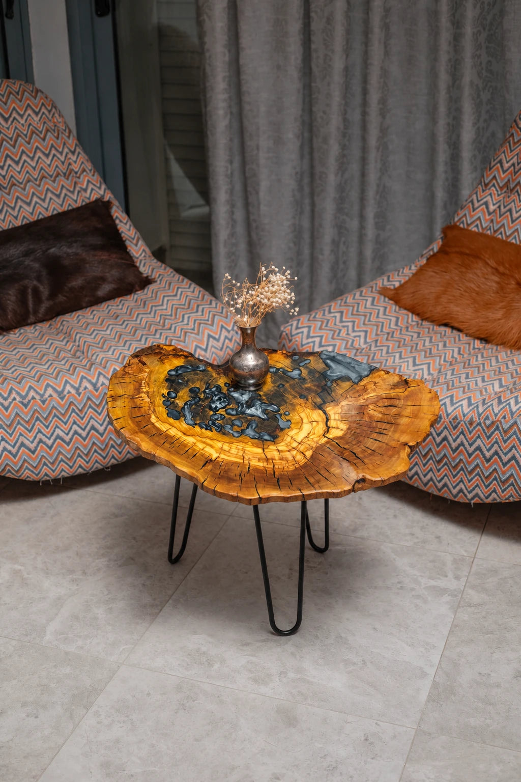 AI-styled view of Zitun Atelier table 092, an olive wood resin side table with black pebble resin, viewed from above between two upholstered armchairs.