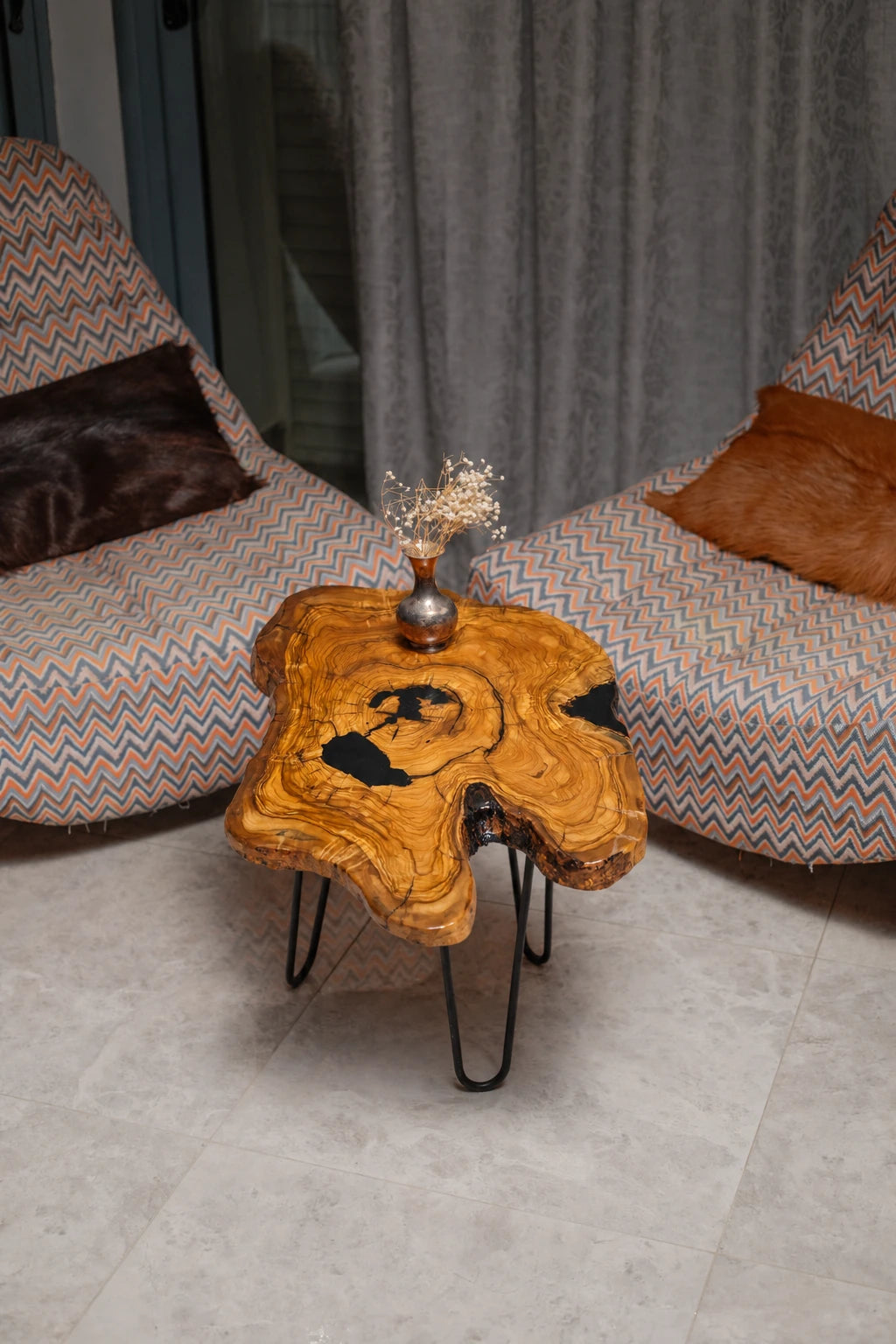 AI-styled view of Zitun Atelier table 094, an olive wood resin side table with black resin inlay, viewed from above between two upholstered armchairs.