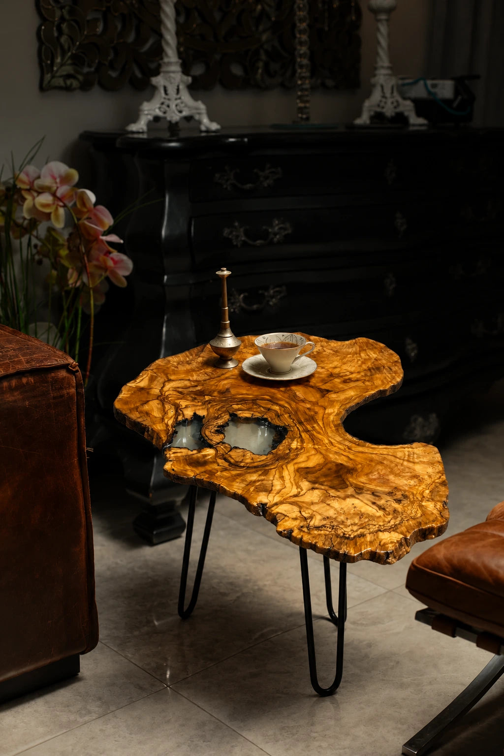 AI-styled view of Zitun Atelier table 095, an olive wood resin side table with white resin inlay, in a dark interior beside leather seating.
