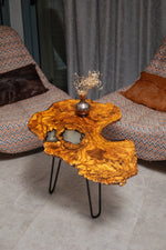 AI-styled view of Zitun Atelier table 095, an olive wood resin side table with white resin inlay, viewed from above between two upholstered armchairs.
