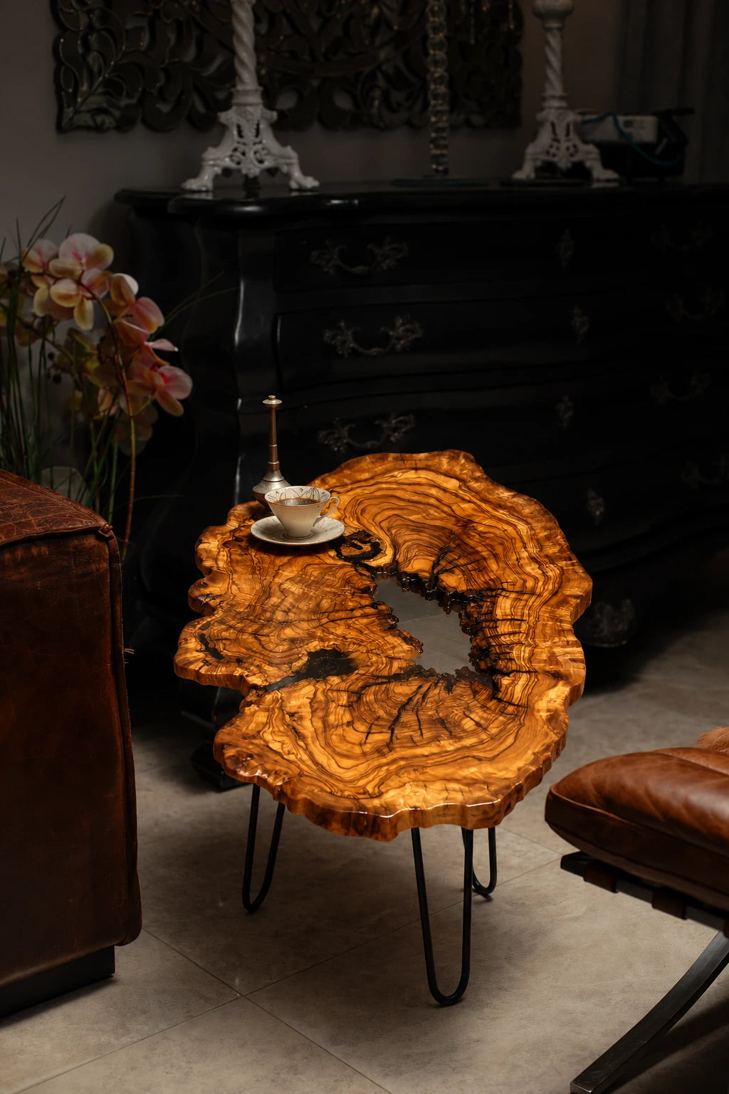 AI-styled view of Zitun Atelier table 096, an olive wood resin small coffee table with white resin river, in a dark interior beside leather seating.