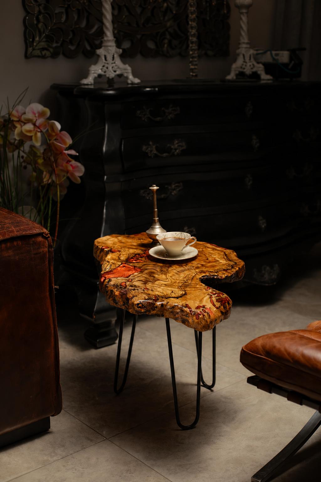 AI-styled view of Zitun Atelier table 098, an olive wood resin side table with copper resin burl, in a dark interior beside leather seating.