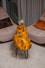 AI-styled view of Zitun Atelier table 099, an olive wood resin small coffee table with black resin knots, viewed from above between two upholstered armchairs.