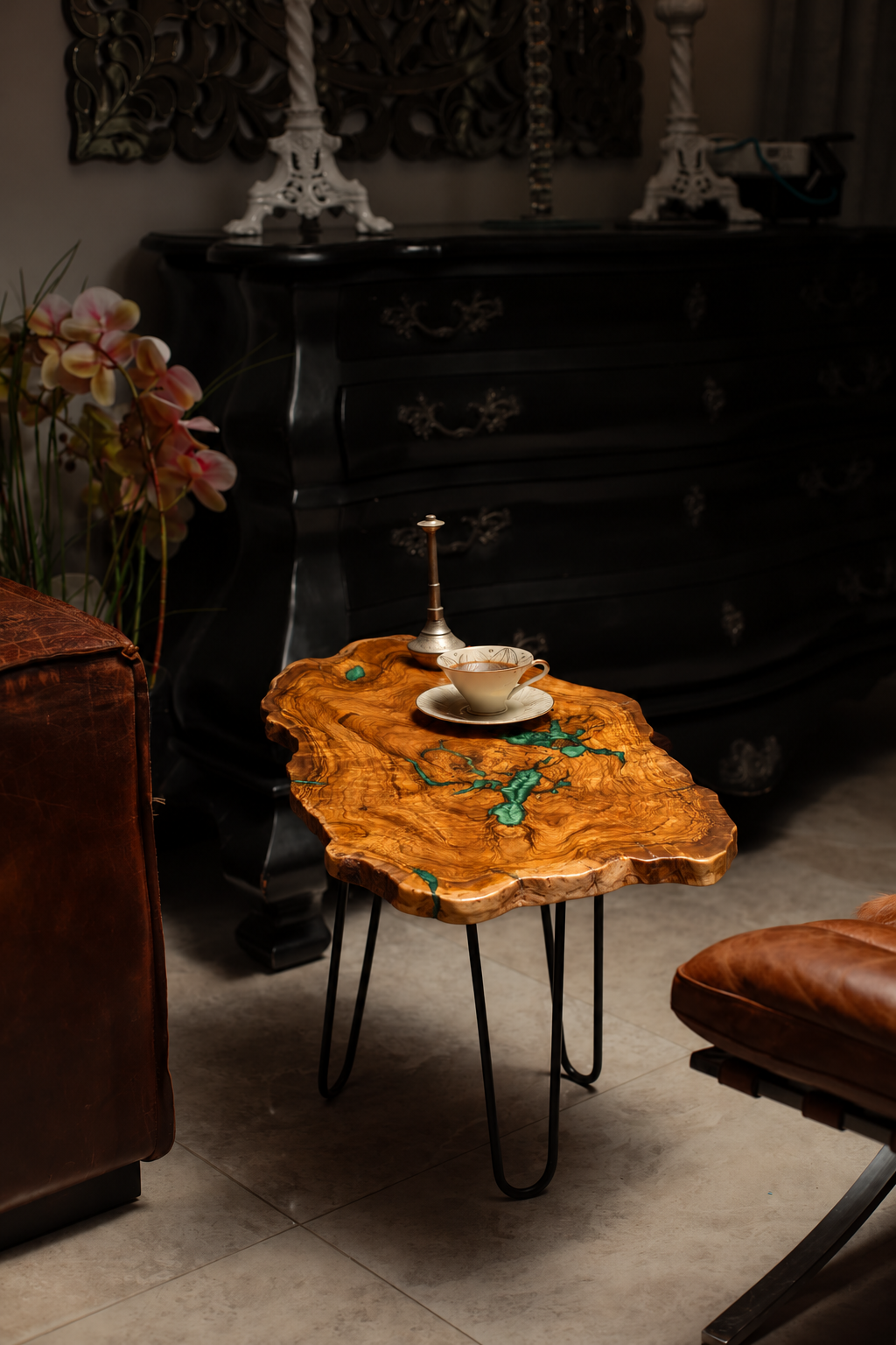 AI-styled view of Zitun Atelier table 100, an olive wood resin small coffee table with green resin veins, in a dark interior beside leather seating.