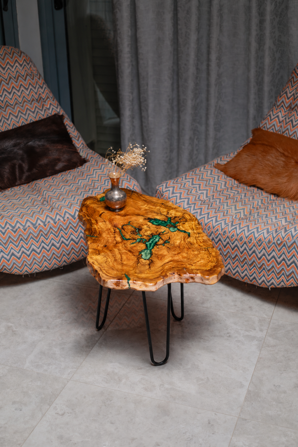 AI-styled view of Zitun Atelier table 100, an olive wood resin small coffee table with green resin veins, viewed from above between two upholstered armchairs.